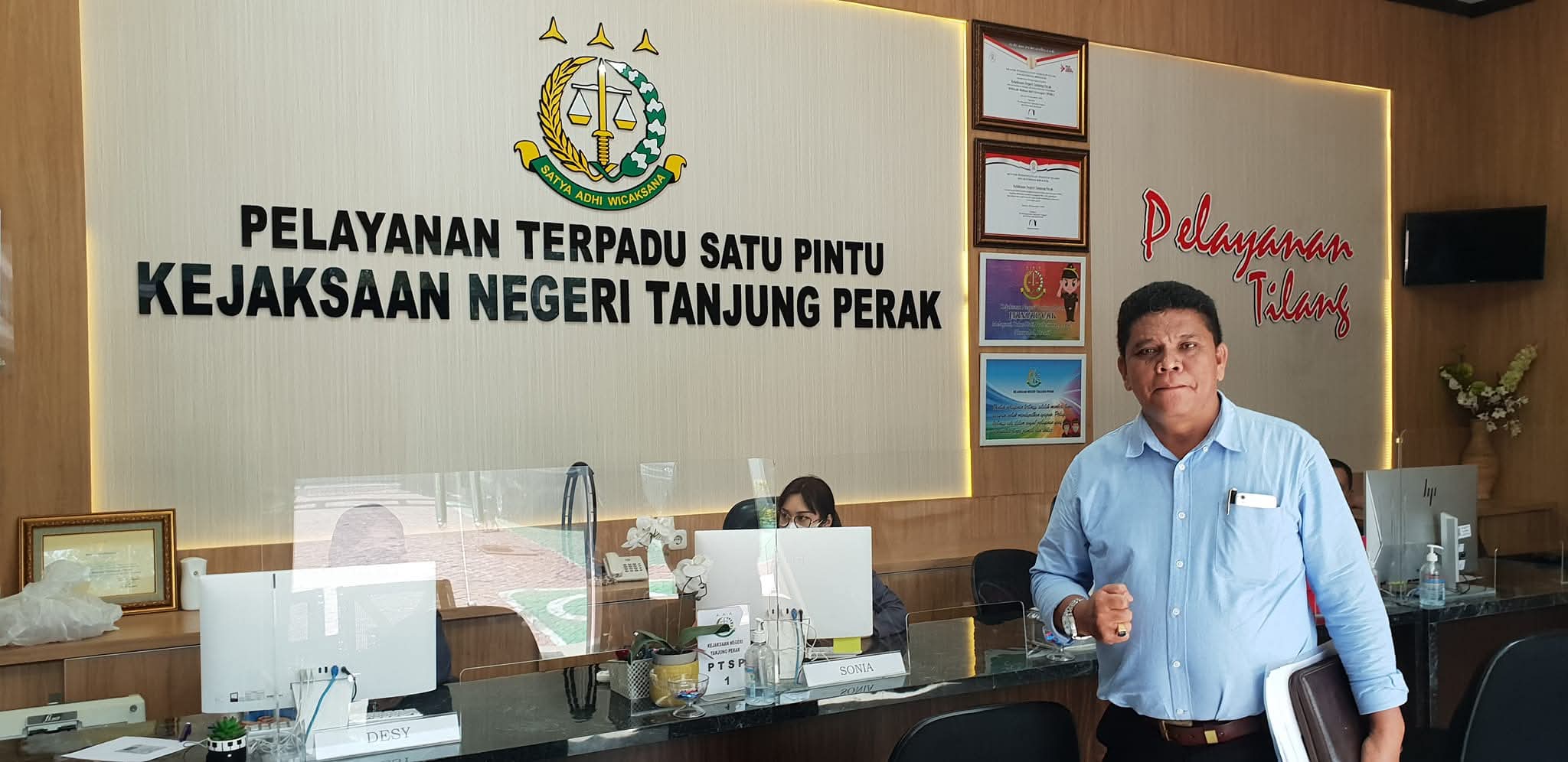 Potret Raymond Simamora, S.H., M.H. berkemeja biru muda saat berada di area Pelayanan Terpadu Satu Pintu (PTSP) Kejaksaan Negeri Tanjung Perak, Surabaya.